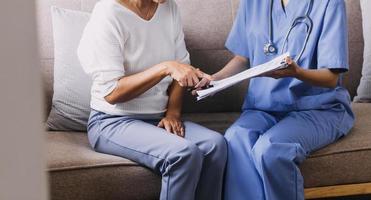 Homecare nursing service and elderly people cardiology healthcare. Close up of young hispanic female doctor nurse check mature caucasian man patient heartbeat using stethoscope during visit photo