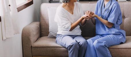 Homecare nursing service and elderly people cardiology healthcare. Close up of young hispanic female doctor nurse check mature caucasian man patient heartbeat using stethoscope during visit photo