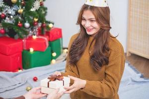 Merry Christmas and Happy Holidays Young woman with a beautiful face in a yellow shirt shows joy with gift boxes in a house with a Christmas tree decorated with Christmas tree.  Portrait before Xmas photo