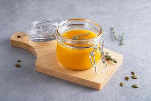 Pumpkin puree soup with pumpkin seeds and thyme in a glass jar photo