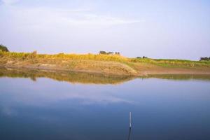 Canal with green grass and vegetation reflected in the water nearby Padma river in Bangladesh photo