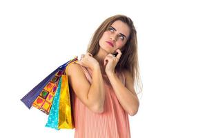 a young girl looks thoughtfully to the side and holding  multicolored bags photo