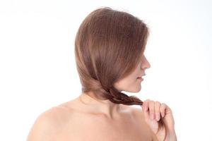 the girl stands with her back to the camera and holds hand hair isolated on white background photo