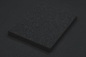 A black sponge on a black background. Black foam rubber on black cloth. The black square of the gasket. photo
