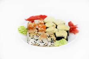 delicioso sushi al horno y rollos en un plato blanco. delicioso desayuno de rollos de arroz de pescado y sushi sobre un fondo blanco. cocina oriental de pescado. cocina japonesa. foto