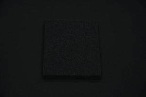 A black sponge on a black background. Black foam rubber on black cloth. The black square of the gasket. photo