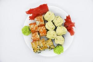 Delicious baked sushi and rolls on a white plate. Delicious breakfast of fish rice rolls and sushi on a white background. Oriental fish cuisine. Japanese cuisine. photo