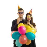chico joven gay con una chica, sosteniendo cerca de los ojos gafas de papel y un montón de globos de aire caliente de colores foto