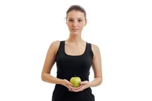 linda chica joven en la camisa negra se ve recta y sosteniendo un primer plano de manzana verde foto