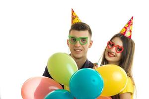 the young smiling boy and cheerful girl wearing colored glasses and carrying balloons photo