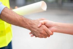 Two engineer shaking hands with deals and success agreement at construction site. Architect and worker handshaking on construction site. photo