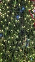 Closeup branches of coniferous tree decorated with glittering balls and shiny garland. Selective focus. Perfect festive content for stories background, vertical banner. photo