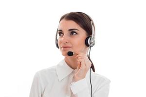 Retrato de una joven y hermosa trabajadora del centro de llamadas con auriculares y micrófono posando aislada de fondo blanco foto