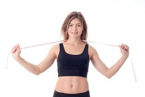 close-up of young slender athletic girl who is smiling and holding a tape measure photo