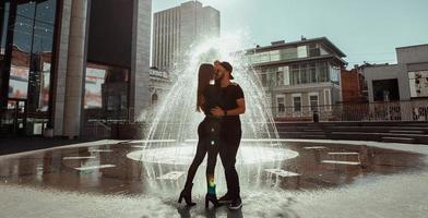 Glamour young couple hugs at the street fountain photo