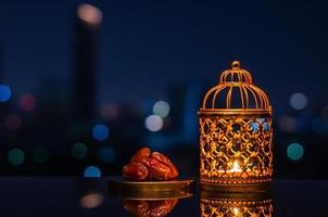 Golden lantern and dates fruit with night sky and city bokeh light background for the Muslim feast of the holy month of Ramadan Kareem. photo