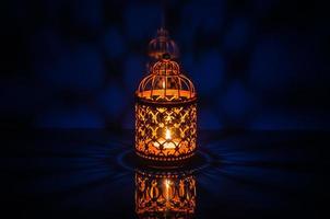Selective focus of golden lantern with reflection from blue background for the Muslim feast of the holy month of Ramadan Kareem. photo