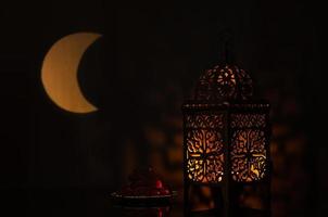 linterna y plato pequeño de dátiles con forma de luna de luz en el fondo para la fiesta musulmana del mes sagrado de ramadán kareem. foto