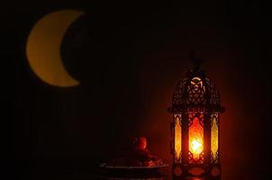 linterna y plato pequeño de dátiles con forma de luna de luz en el fondo para la fiesta musulmana del mes sagrado de ramadán kareem. foto