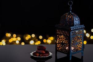 linterna y dátiles de frutas en un fondo oscuro con luz bokeh para la fiesta musulmana del mes sagrado de ramadán kareem. foto