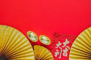 Chinese new year concept with red envelope packets or ang bao word mean auspice and ingots word mean wealth on red background with golden oriental fans. photo