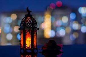 foco selectivo de linterna y plato pequeño de dátiles con fondo de edificio de apartamentos para la fiesta musulmana del mes sagrado de ramadán kareem. foto
