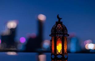 Selective focus of lantern that have moon symbol on top with city background for the Muslim feast of the holy month of Ramadan Kareem. photo