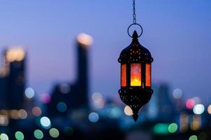 Hanging lantern with night sky and city bokeh light background for the Muslim feast of the holy month of Ramadan Kareem. photo