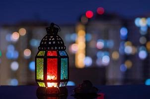 linterna y plato pequeño de dátiles con fondo de edificio de apartamentos para la fiesta musulmana del mes sagrado de ramadán kareem. foto