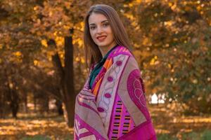 young girl stands in the Park in  large scarf on the shoulders photo