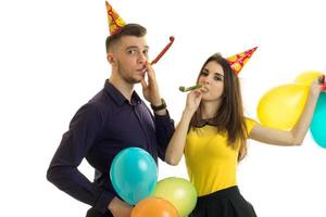 portrait of cheerful young couple blowing in horns photo