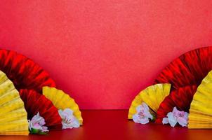 Selective focus on some golden and red oriental fans with peach blossom on red background for Chinese new year concept. photo