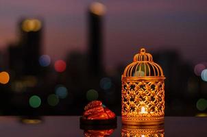 Golden lantern and dates fruit with dusk sky and city bokeh light background for the Muslim feast of the holy month of Ramadan Kareem. photo
