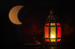 linterna y plato pequeño de dátiles con forma de luna de luz en el fondo para la fiesta musulmana del mes sagrado de ramadán kareem. foto