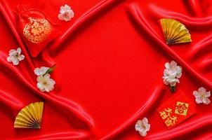 fondo de tela de satén rojo con la palabra bolsa roja significa riqueza y paquetes de sobres rojos o la palabra ang bao significa riqueza, suerte con los fanáticos dorados por el concepto de año nuevo chino.
