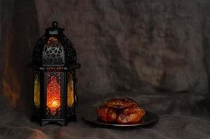 Black lantern and dates fruit on dark background for the Muslim feast of the holy month of Ramadan Kareem. photo