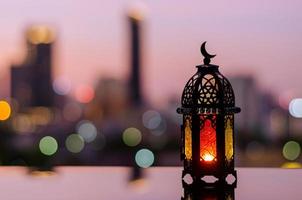 Lantern with dusk sky and city bokeh light background for the Muslim feast of the holy month of Ramadan Kareem. photo