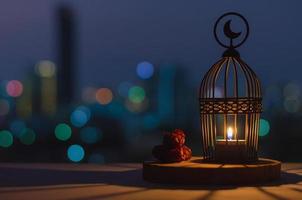 Lantern that have moon symbol on top and dates fruit put on wooden tray with colorful city bokeh lights for the Muslim feast of the holy month of Ramadan Kareem. photo