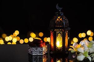 Lantern and dates fruit with white orchid flower on bokeh light background for the Muslim feast of the holy month of Ramadan Kareem. photo