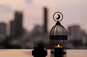 linterna que tiene el símbolo de la luna en la parte superior y un pequeño plato de fruta de dátiles con el cielo del amanecer y el fondo de la ciudad para la fiesta musulmana del mes sagrado del ramadán kareem. foto
