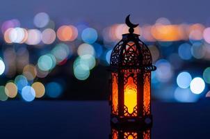 Selective focus of lantern that have moon symbol on top with city bokeh light background for the Muslim feast of the holy month of Ramadan Kareem.