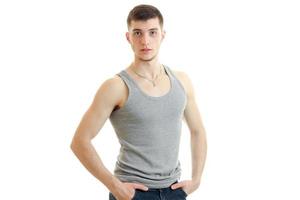 handsome young guy standing in a t-shirt and keeps his hands in his pockets photo