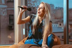 hermosa joven rubia cantando karaoke con un micrófono foto