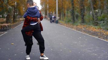 heureux enfant d'âge préscolaire sautant jusqu'à ses belles mains de mères au chaud parc d'automne video