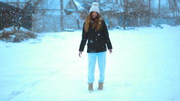 chica divertida en invierno afuera en una tormenta de nieve posando video