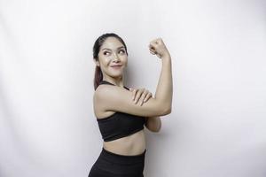 emocionada mujer deportiva asiática con ropa deportiva que muestra un gesto fuerte levantando los brazos y los músculos sonriendo con orgullo foto