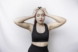 A portrait of an sporty Asian woman wearing a sportswear isolated by white background looks depressed photo