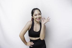 Excited sporty Asian woman wearing a sportswear is giving an OK hand gesture isolated by a white background photo