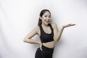 Excited Asian sporty woman wearing sportwear pointing at the copy space beside her, isolated by white background photo