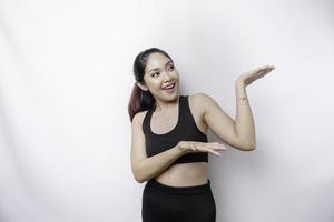 Excited Asian sporty woman wearing sportswear pointing at the copy space on top of her, isolated by white background photo